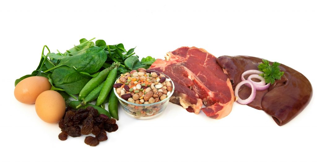 Iron-rich foods, including eggs, spinach, peas, beans, red meat, liver, and raisins. Isolated on white.