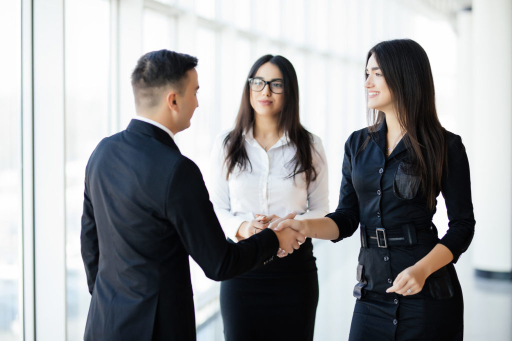 Businessman And Businesswoman Shaking Hands In Office